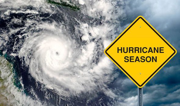 A swirling hurricane is shown in satellite view beside a yellow road sign warning of "Hurricane Season" under a cloudy sky.